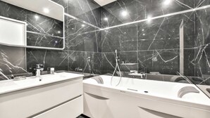 A modern bathroom with a large mirror, two sinks, and a bathtub.