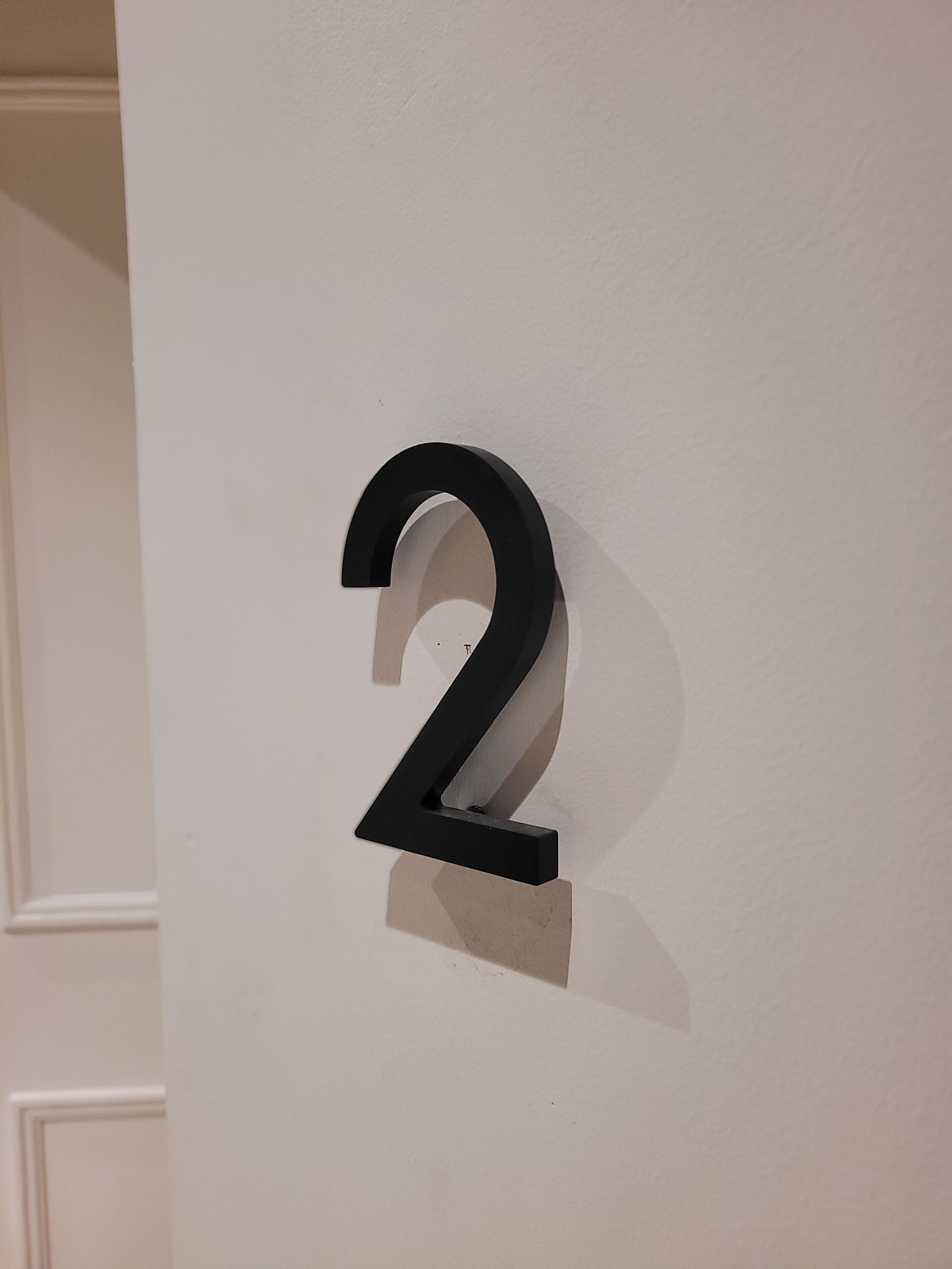 A black number '2' mounted on a white wall.