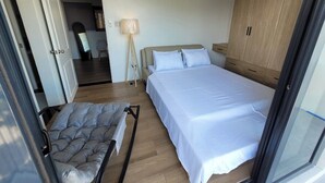 A modern bedroom with a large bed, a wardrobe, and a bedside table. - Ganada Suites 2 (Angeles)