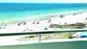 A beach with a clear view of the ocean, a sandy shore, and a pool area.