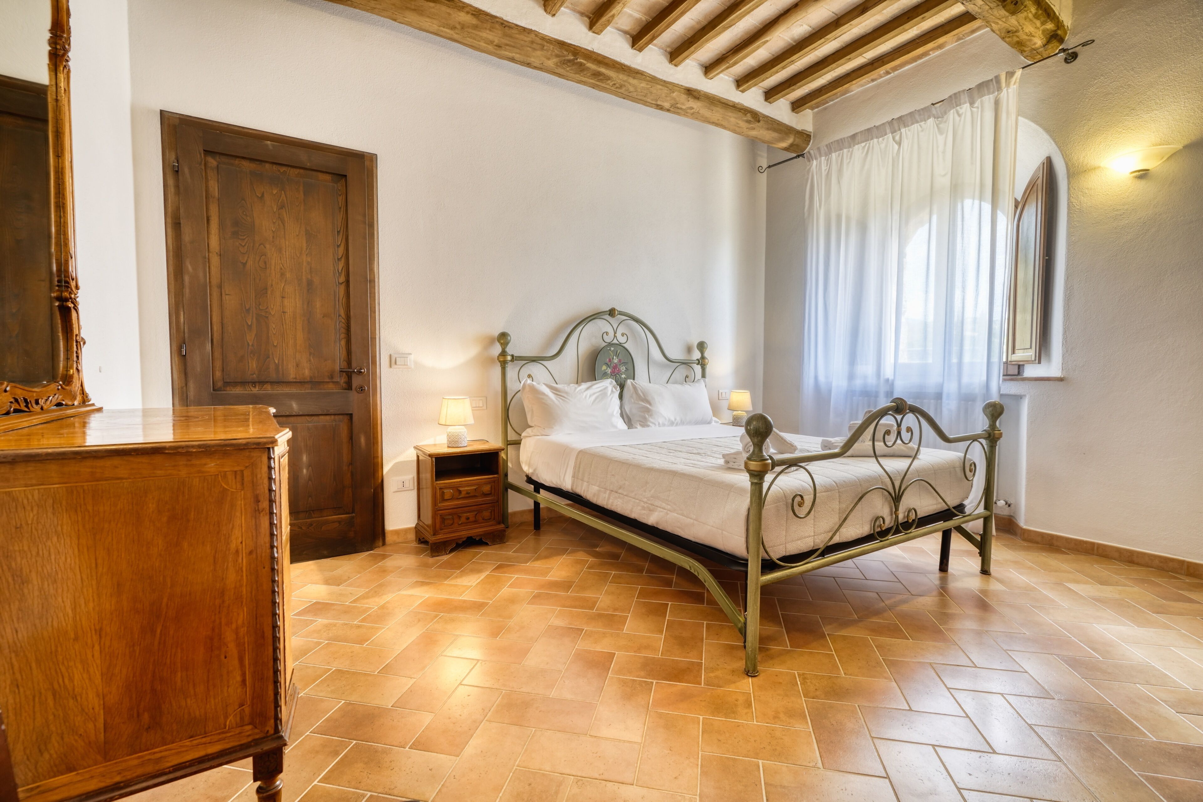 Una camera da letto con un letto, una cassettiera in legno e una porta.