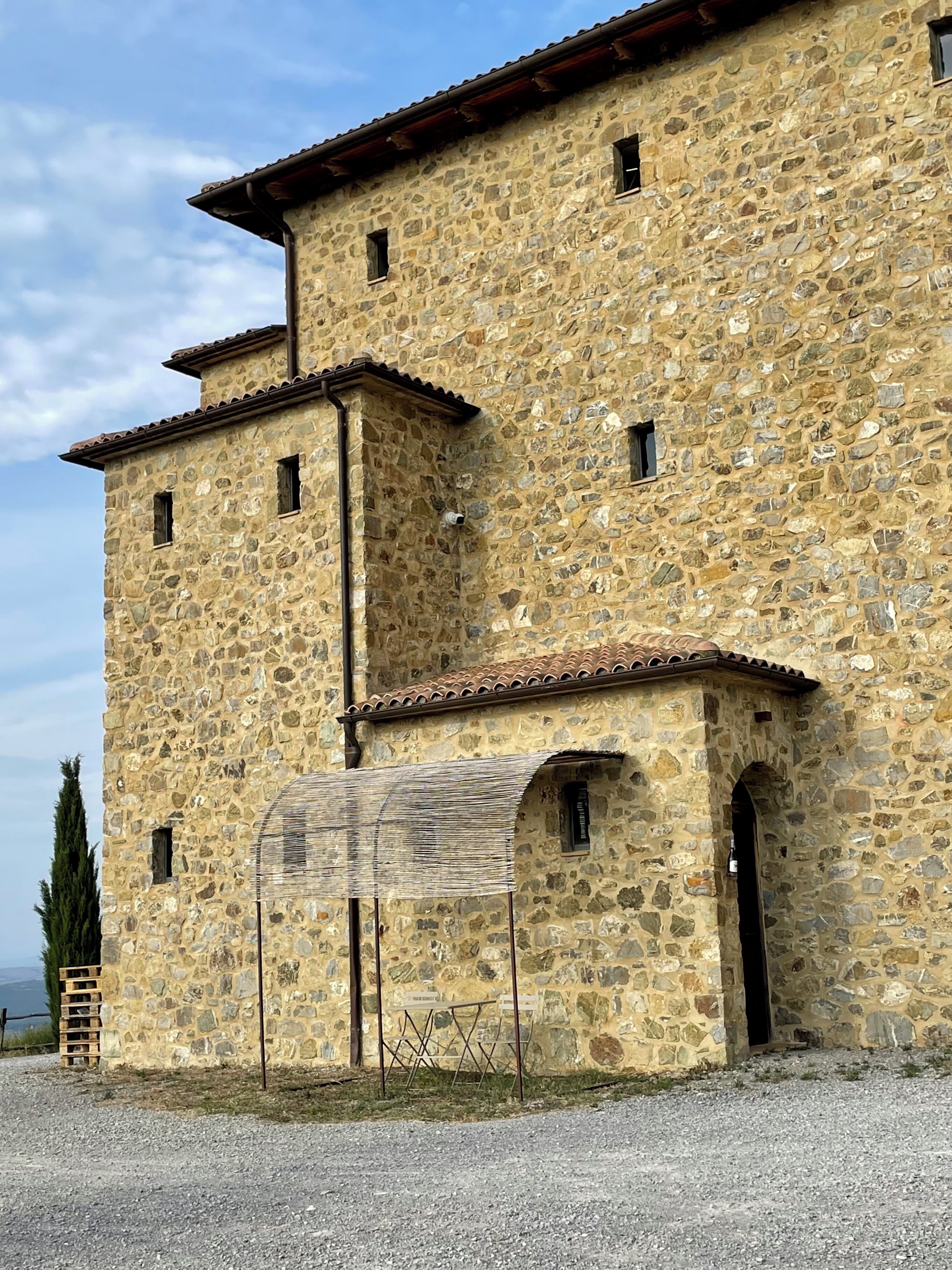 Un edificio de piedra con techo de tejas, varias ventanas y un porche cubierto.