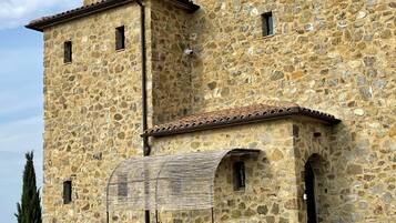 Un edificio de piedra con techo de tejas, varias ventanas y un porche cubierto.