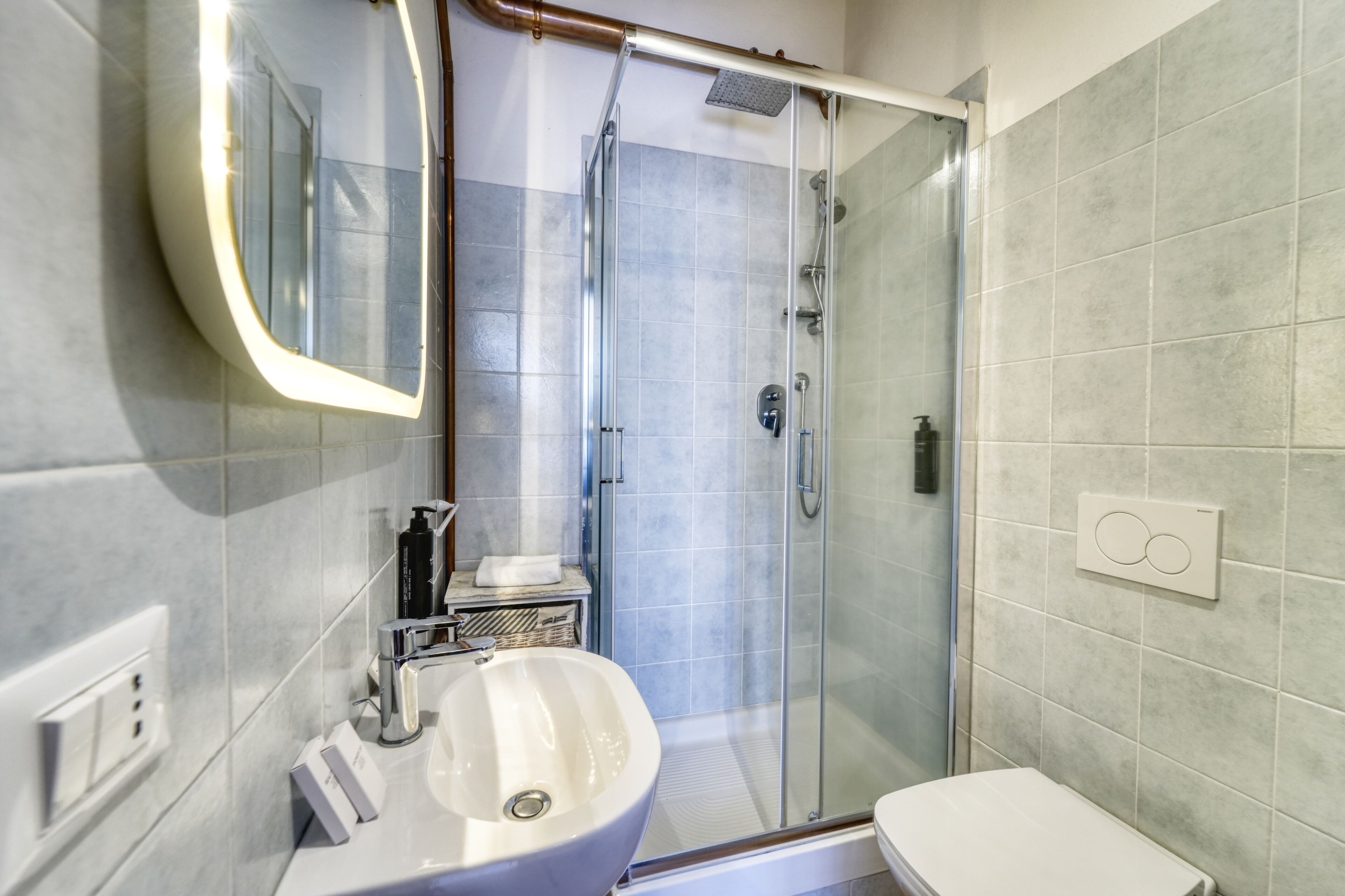 A modern bathroom with a glass shower enclosure, a white sink, and a toilet.