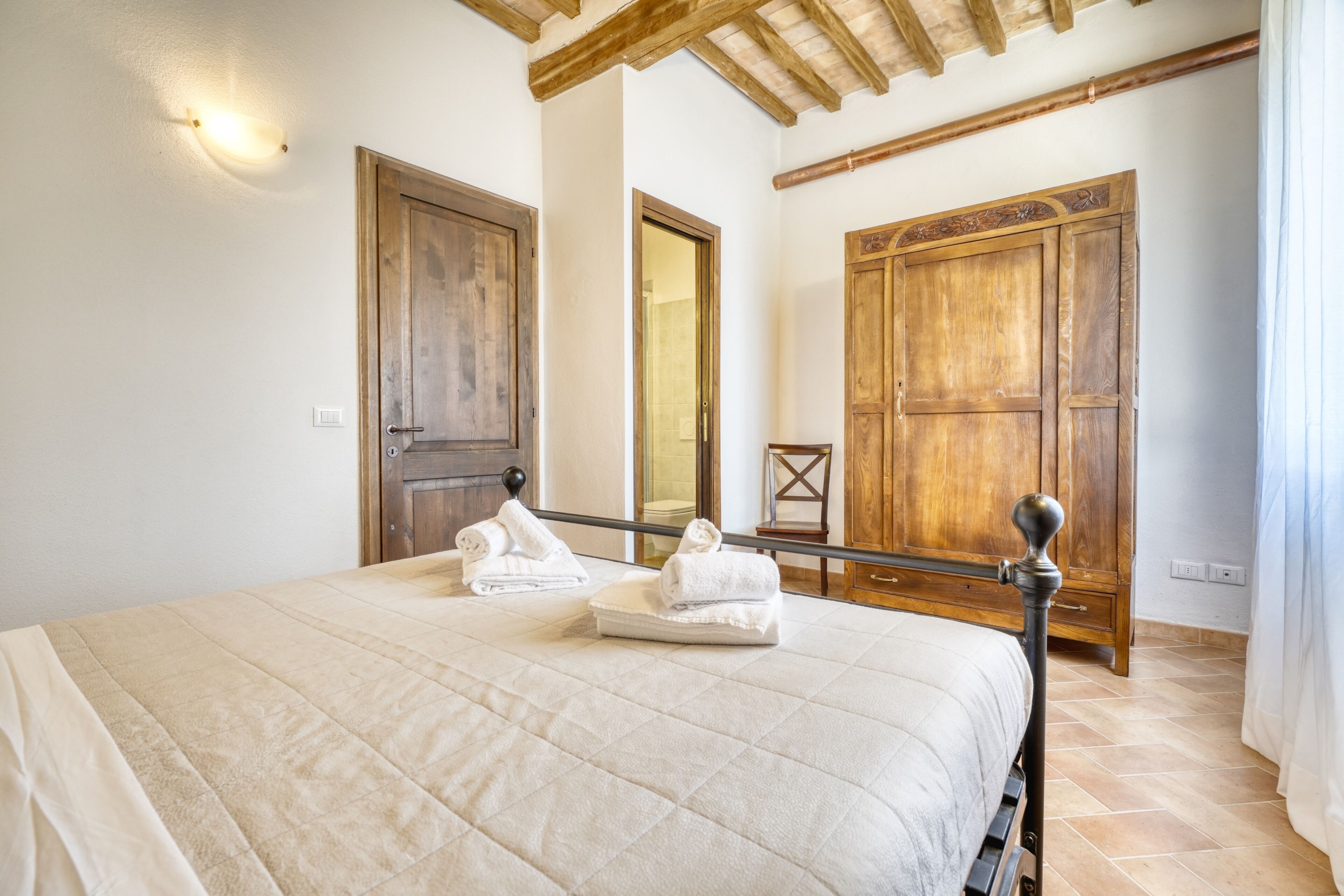 Une chambre à coucher avec un lit, deux portes en bois, un miroir et une armoire en bois.
