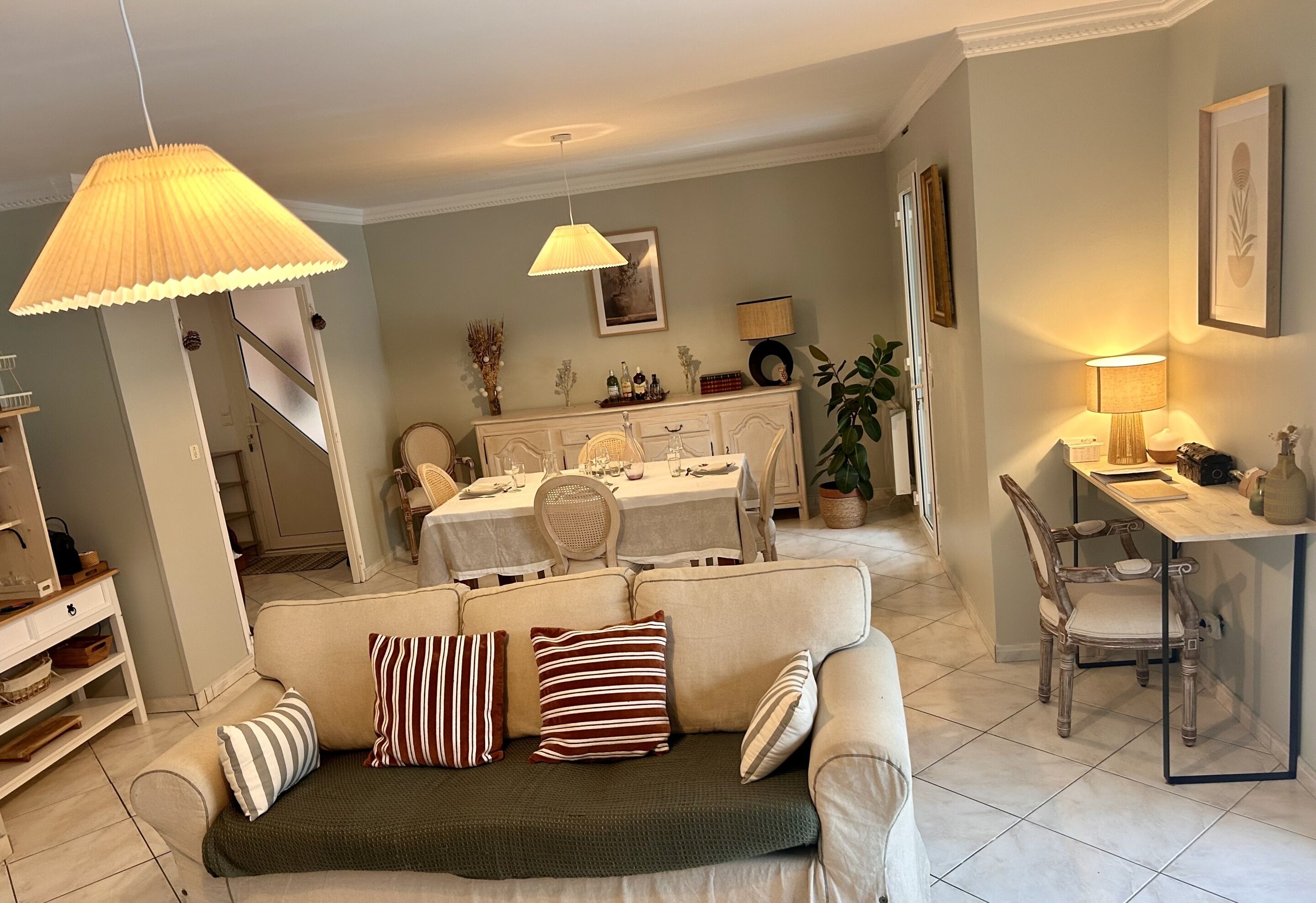Un salon comprenant un canapé, une table à manger et des chaises. Un escalier mène à un autre niveau.