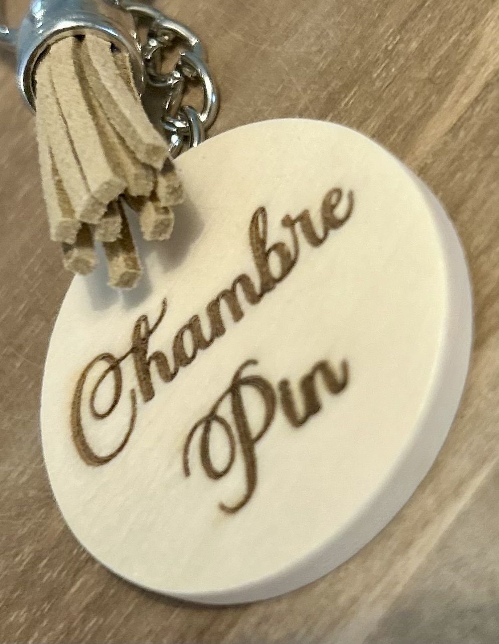 Un llavero redondo de madera con la inscripción 'Chambre Pin'.