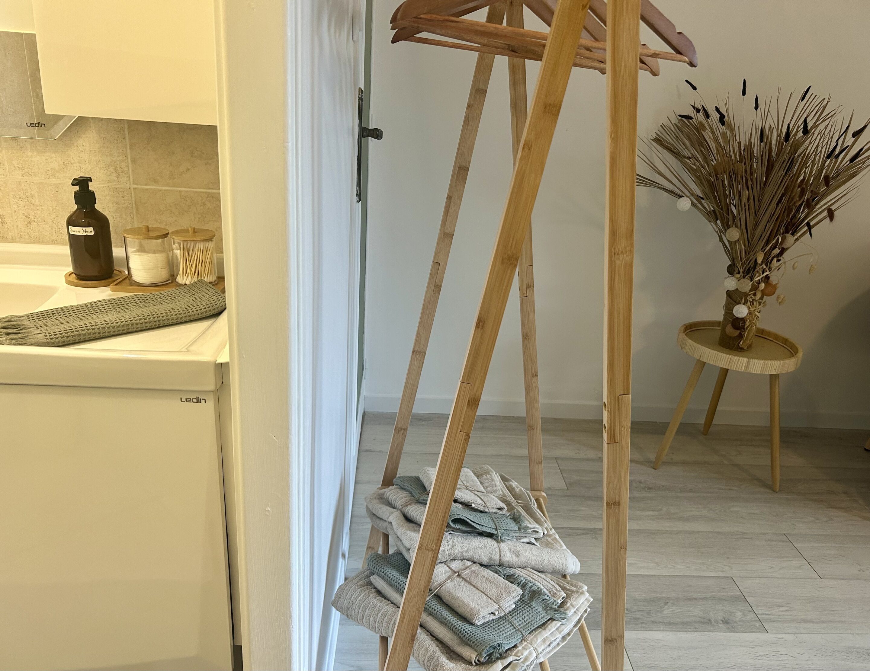 A kitchen with a wooden drying rack holding towels, a soap dispenser, and a candle on the counter.
