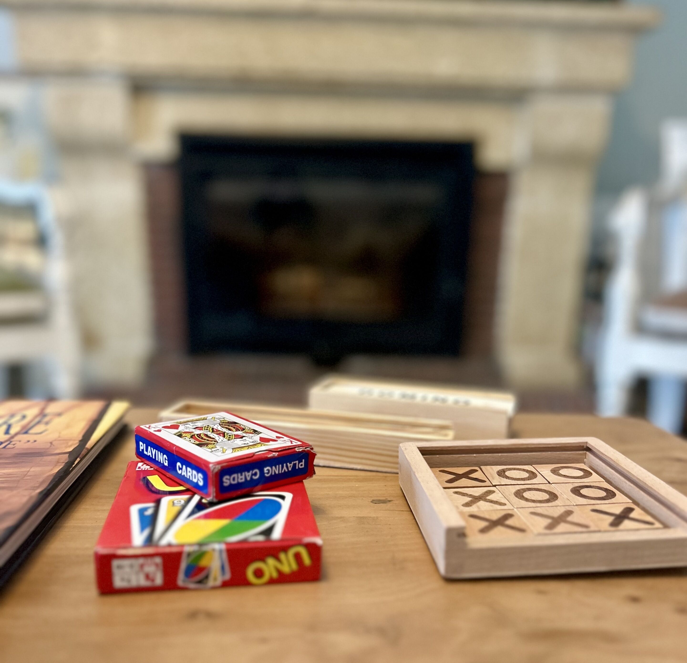 A wooden table with playing cards and a Scrabble game.