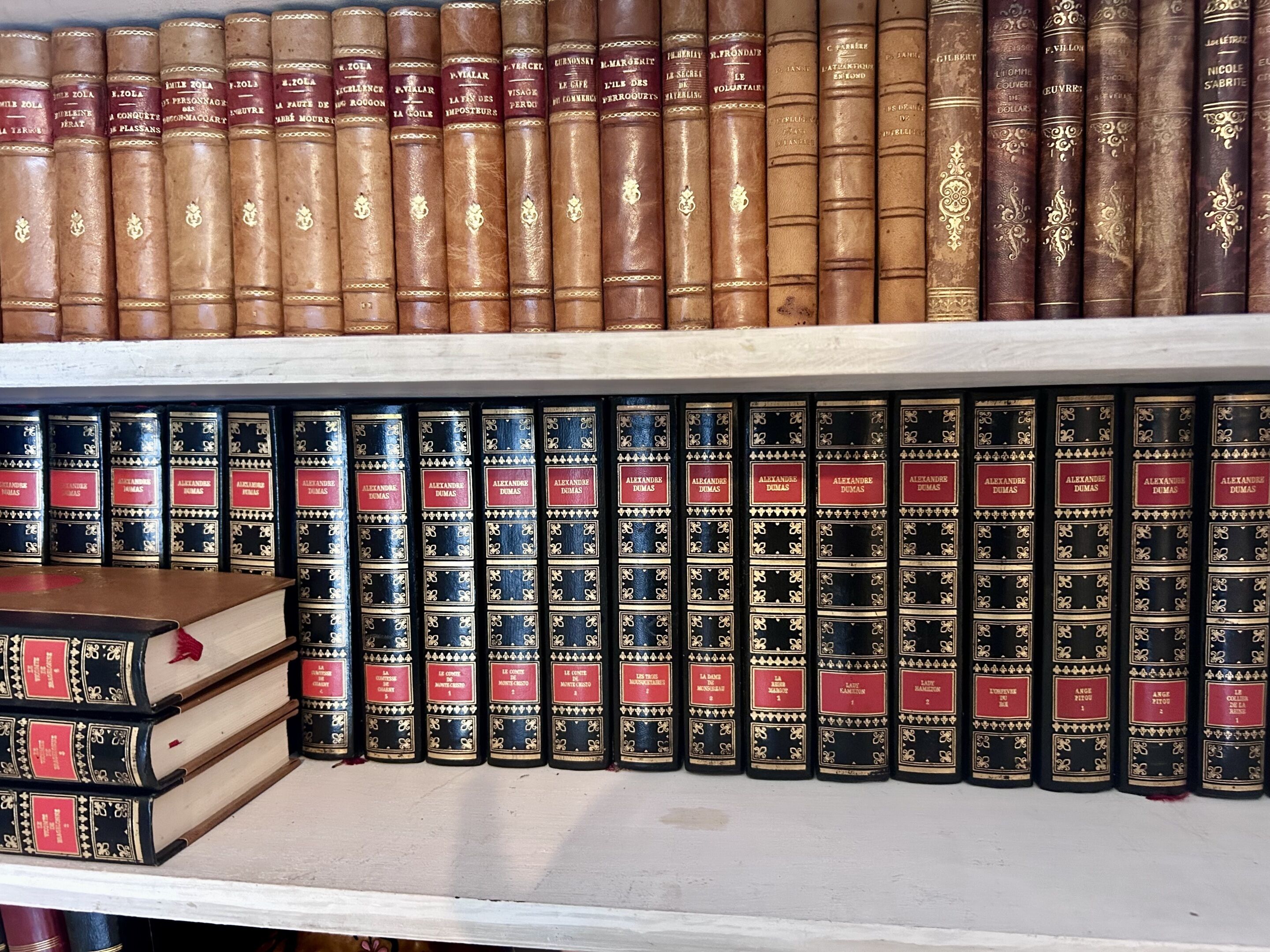 Een boekenplank met rijen boeken, waarvan sommige goudlettertype hebben en andere rode labels.