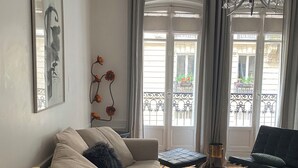 Una sala de estar con sofá, una mesita, una mesa de centro, una lámpara y un balcón con vistas.
