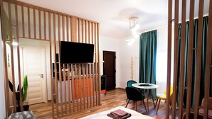 Une chambre d’hôtel comprenant un lit, une télévision, un coin repas avec des chaises et une cloison en bois.
