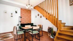 Un salon moderne avec un mur en briques, un escalier en bois et un coin repas comprenant une table et des chaises.