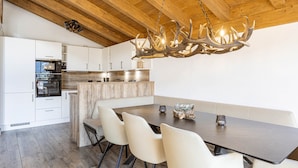 A modern kitchen with white cabinets, a built-in oven, and a wooden ceiling. - Superior Ferienhaus # 4B mit Sauna (Uttendorf)