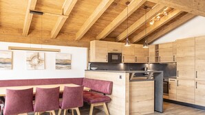 A modern kitchen with wooden cabinets, a central island, and a dining area with red upholstered chairs.