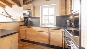 A modern kitchen with wooden cabinets, a black countertop, and a window providing natural light.