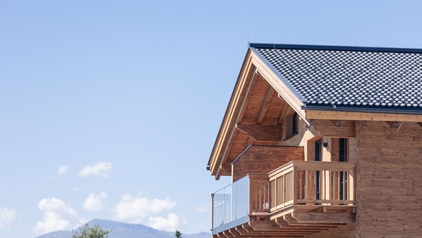 A wooden building with a balcony and a mountain in the background.