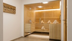 Un cuarto de sauna con bancos de madera, una pared de vidrio y un banco con toallas.