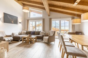 Relax in this spacious living area with a high ceiling and large windows offering a view of the outdoors.