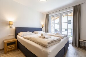 A hotel room with a large bed, two bedside tables, and a window with curtains.