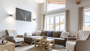 Una sala de estar acogedora con un sofá, sillones, una mesa de centro y un cuadro de un ciervo en la pared.