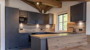 Une cuisine moderne avec des meubles de couleur sombre, un îlot central en bois et des appareils électroménagers intégrés.