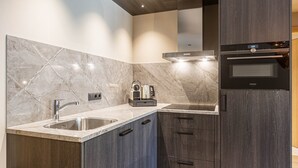 A modern kitchen with a marble backsplash, stainless steel sink, and built-in oven. - Superior 1-Bedroom Apartment (Schruns)