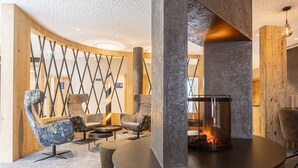 Un espace de détente moderne avec une cheminée en pierre, des sièges confortables et un mur de séparation en bois.