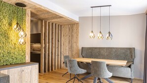 Ein moderner Essbereich mit Holztisch, grau gepolsterten Stühlen und einer grünen Wand mit strukturierter Oberfläche.