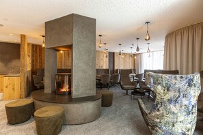 A modern lounge area with a central fireplace, wooden accents, and contemporary seating.