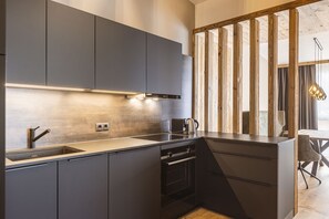 Cozinha moderna com armários escuros, pia de aço inoxidável e forno embutido.