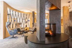 A modern lounge area with a round table, two armchairs, and a fireplace.