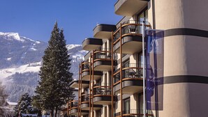 Ein Hotel mit mehreren Balkonen und Blick auf die Berge, mit einem Schild, das 'Alps Resorts' anwirbt.