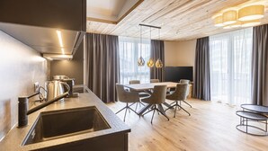 Una cucina moderna con una grande isola, zona pranzo con tavolo e sedie, e un soffitto in legno.