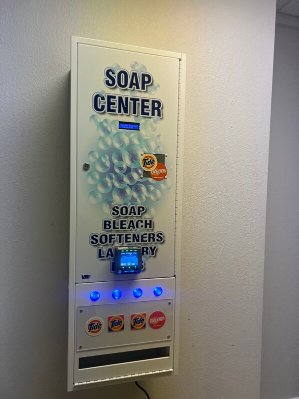 A soap dispenser wall-mounted on a textured wall.