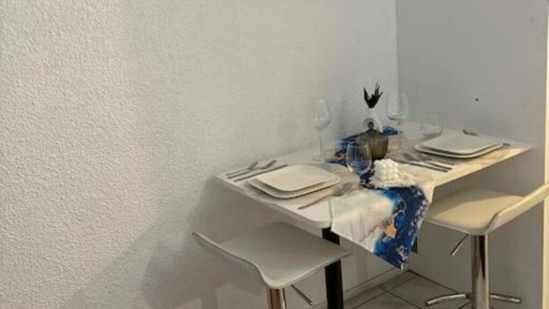 A dining area with a white table set for four, including plates, cutlery, and glasses.