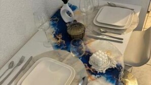 Une table mise pour le repas, avec de la vaisselle en verre, des assiettes et des couverts.
