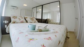 Quarto com cama, mesa de cabeceira, espelho e guarda-roupa.