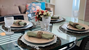 Mesa de jantar posta com pratos, talheres e elementos decorativos.