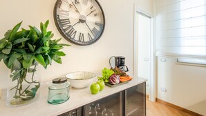 Une cuisine avec une horloge murale, une plante, une machine à café et des produits frais.