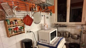 Une cuisine compacte équipée d’un four à micro-ondes, d’une cuisinière et de divers ustensiles fixés au mur.