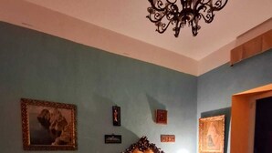 Une chambre à coucher avec un lit, une chaise, un lustre et des tableaux encadrés accrochés au mur.