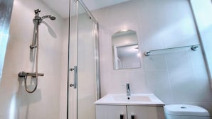 A modern bathroom with a glass shower enclosure, a white sink, and a toilet.
