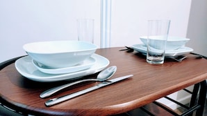 A dining table with white plates, bowls, a glass, a knife, and a spoon.