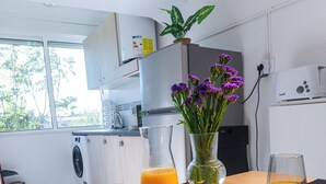 A modern kitchen with a washing machine, a coffee machine, and a dining table set with breakfast items.