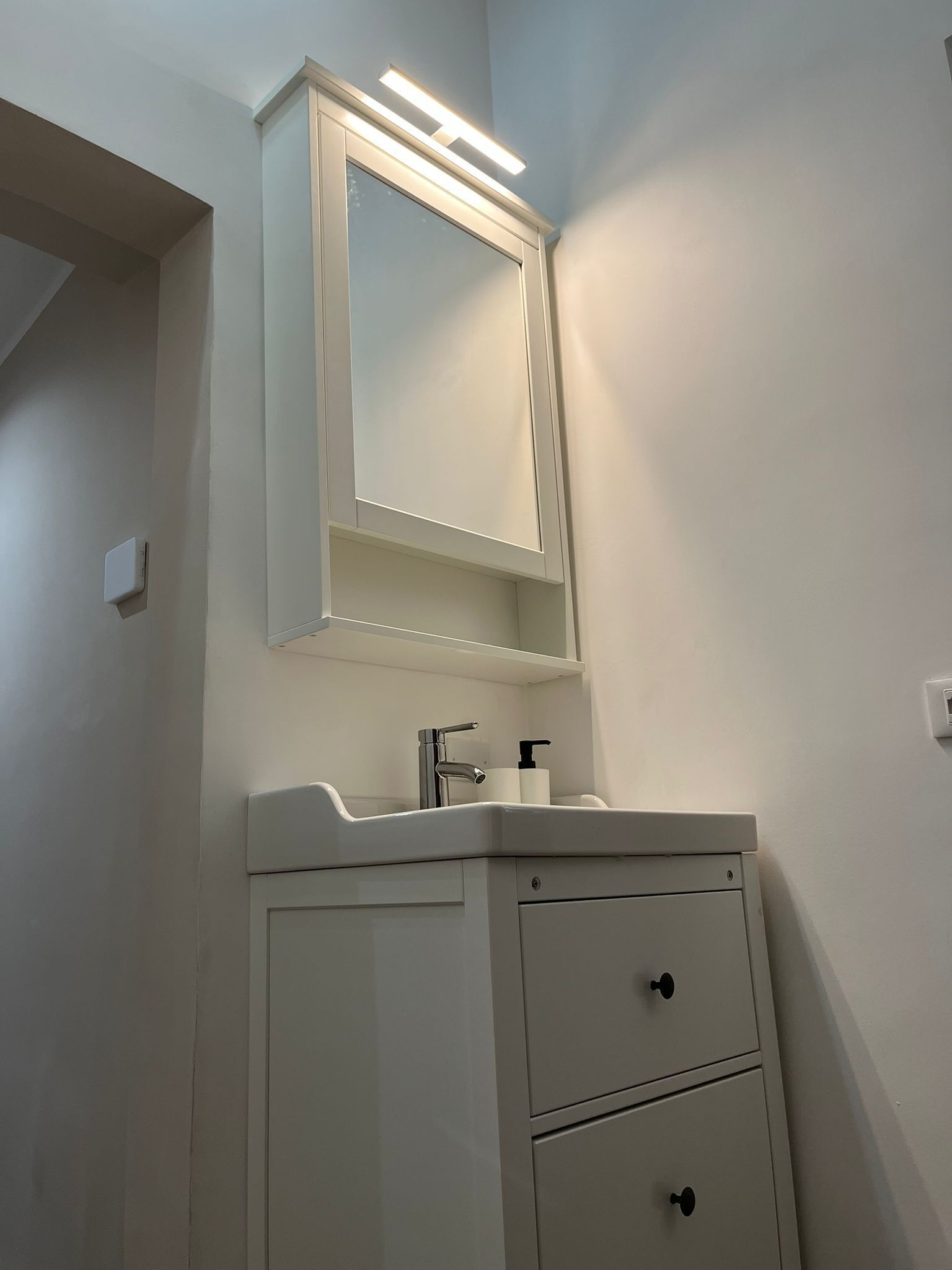 A bathroom with a white vanity, a mirror, a sink, and a toilet.