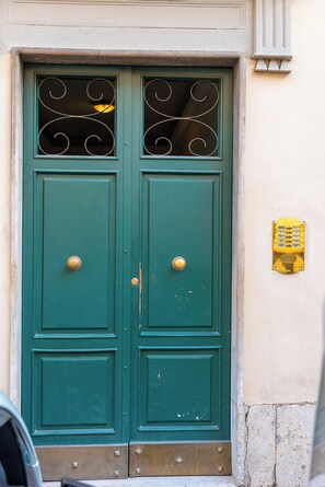 Une porte à deux battants, peinte en vert, avec une poignée de porte en laiton et une petite plaque en laiton fixée au-dessus.