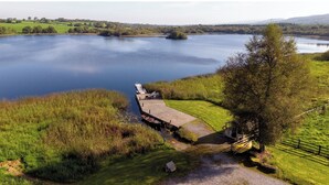 A lakeside property with a dock, grassy areas, and a small building. - Luxury and elegant lakeside lodges, Boating activities and pet friendly.
 (Sixmilebridge)