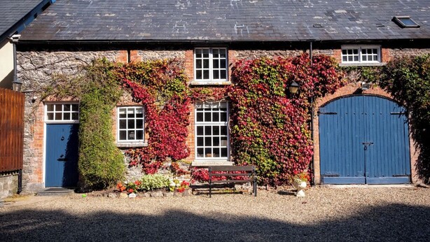 A stone building with a blue door and windows, surrounded by gravel and a bench. - Luxury and elegant lakeside lodges, Boating activities and pet friendly.
 (Sixmilebridge)