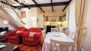 A cozy living room with a red sofa set, a dining table with chairs, and a kitchen in the background. - Luxury and elegant lakeside lodges, Boating activities and pet friendly.
 (Sixmilebridge)